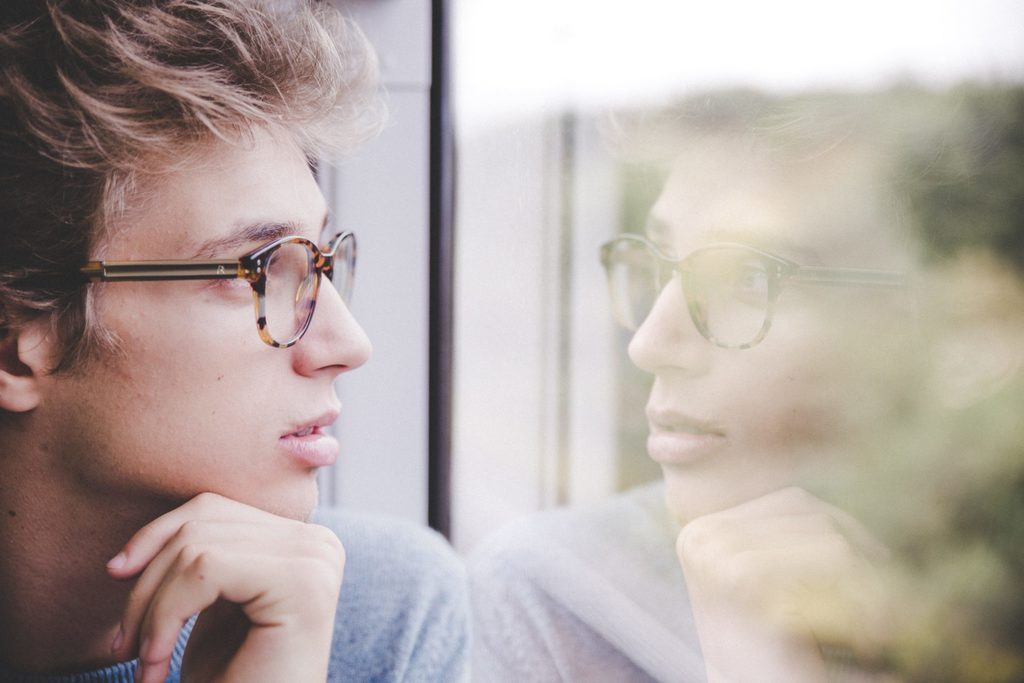 Eduquer AVec Sagesse - Photo by Laurenz Kleinheider on Unsplash- Jeune homme regardant par une fenetre avec son reflet dans la vitre